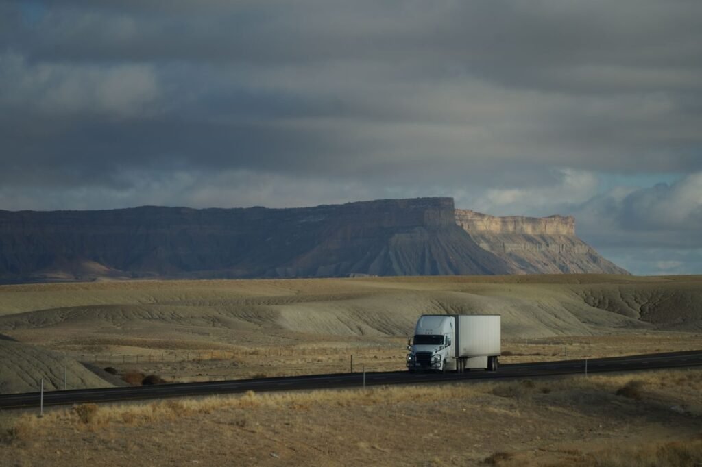 Freight truck crossing a vast landscape under a dramatic sky