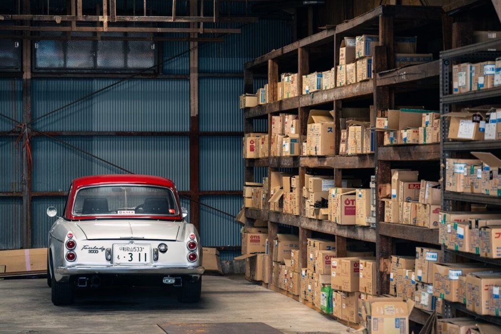 A vehicle parked beside warehouse shelves stacked with boxes
