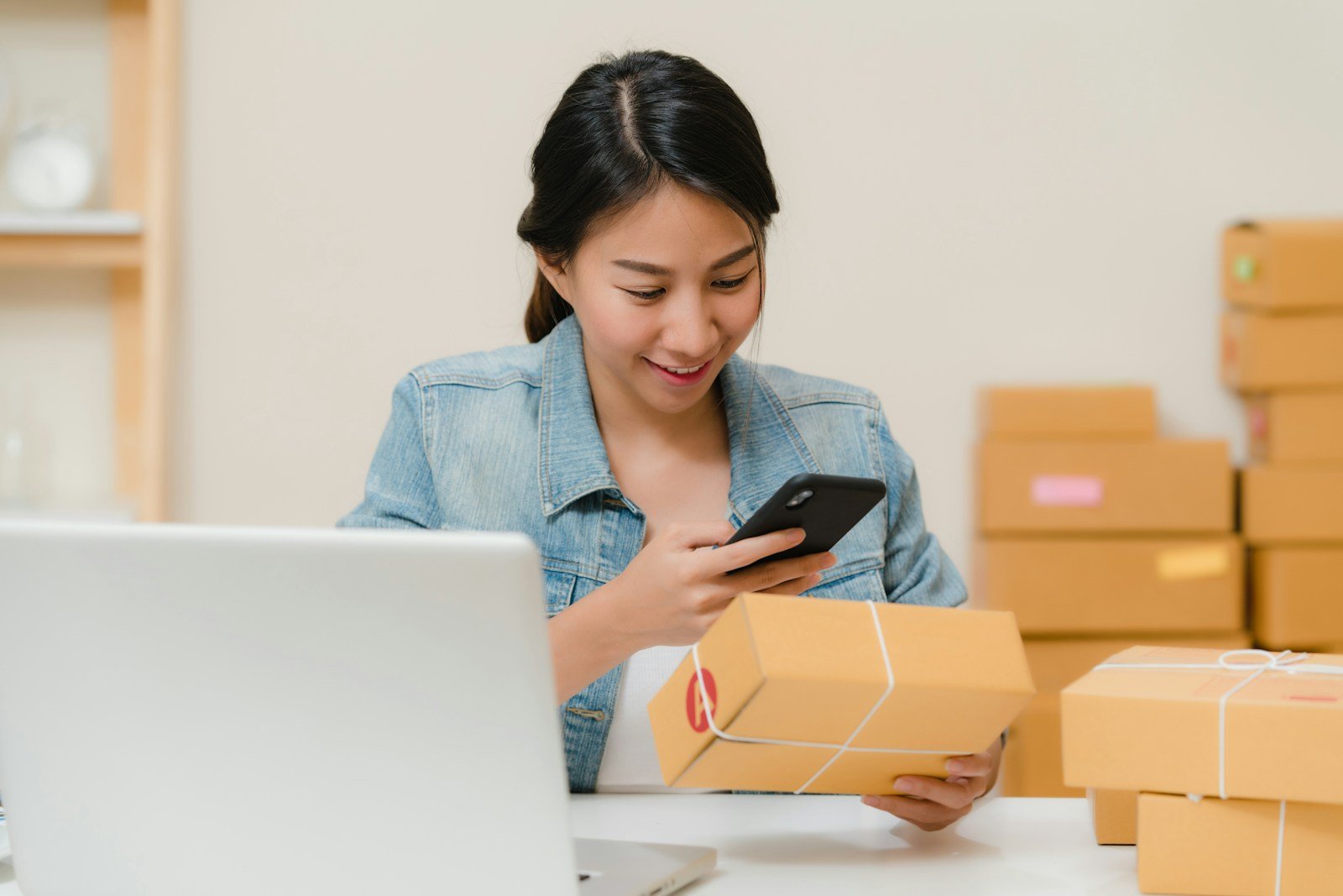 Online store owner checking a parcel beside a laptop and packed orders