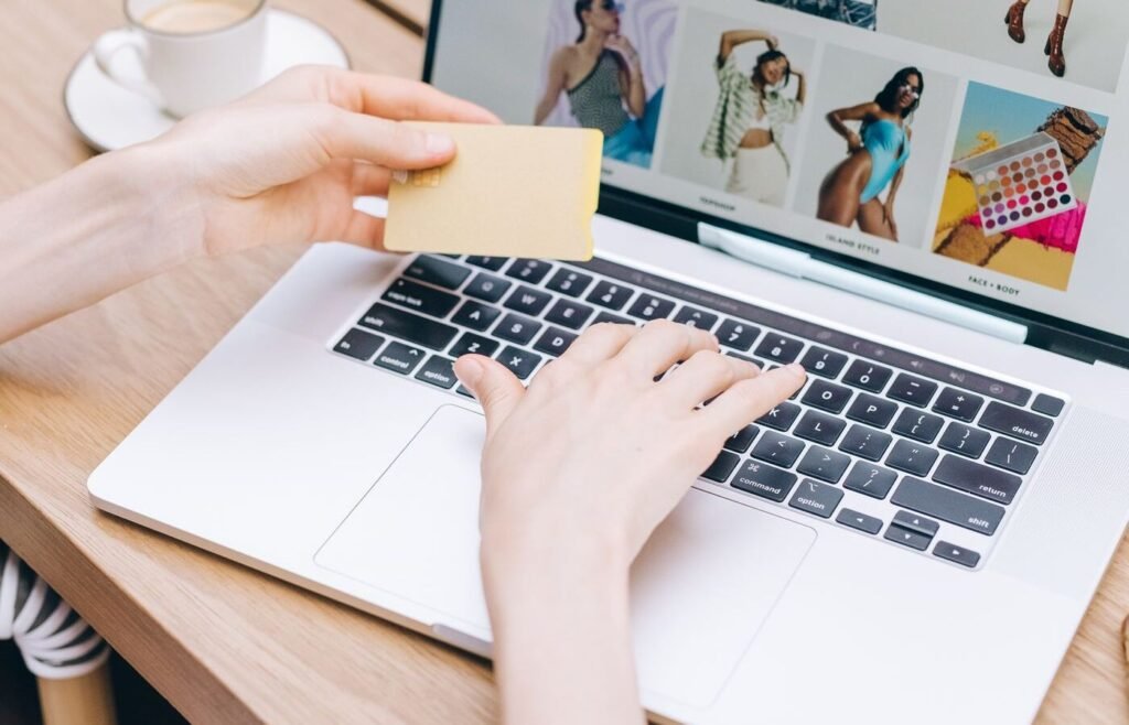 Hands holding a payment card while completing an online store checkout on a laptop