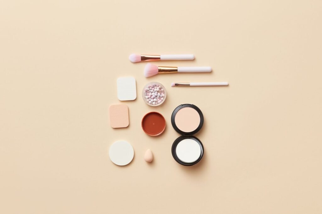 Makeup brushes and cosmetics arranged on a neutral background