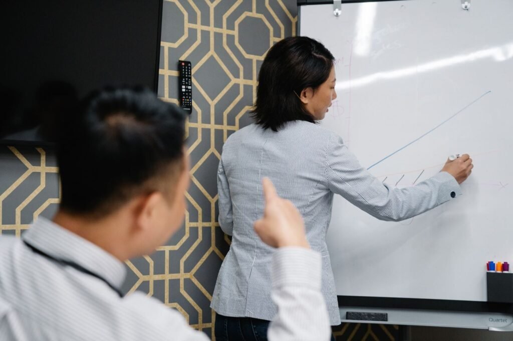 Two specialists reviewing a conversion chart on a whiteboard