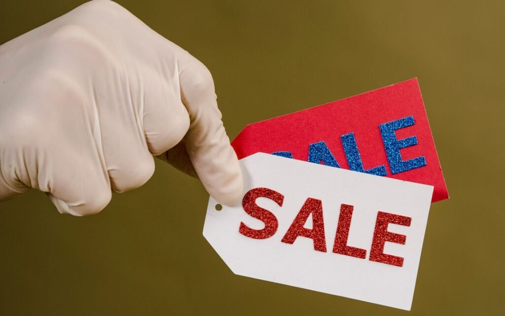 Hand holding red and white sale tags, the discount decision this calculator prices