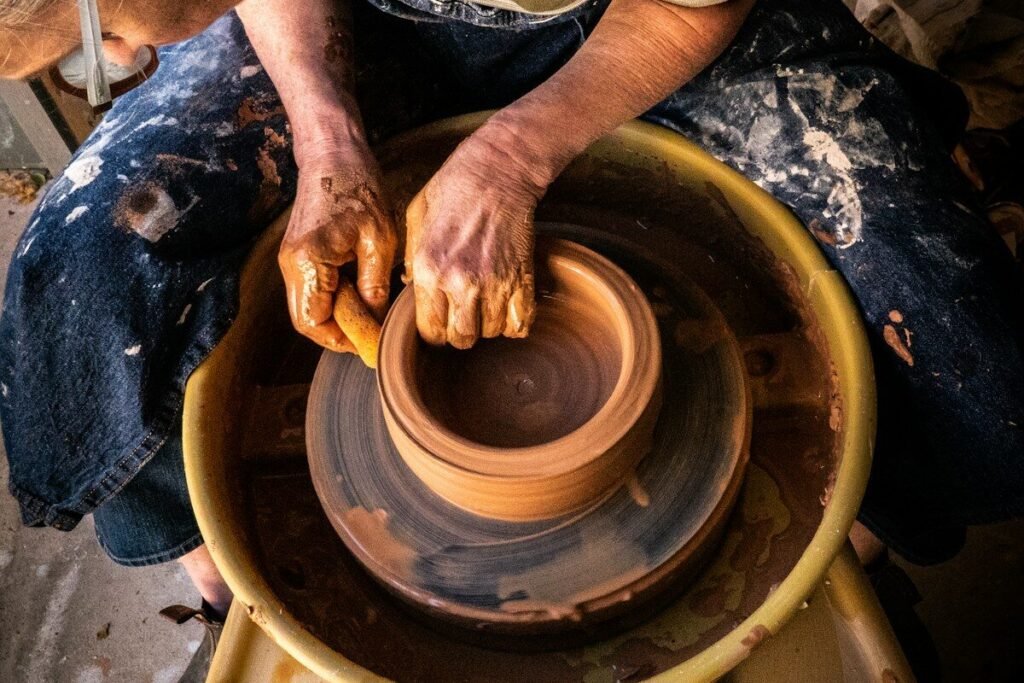 A maker forming a clay pot by hand