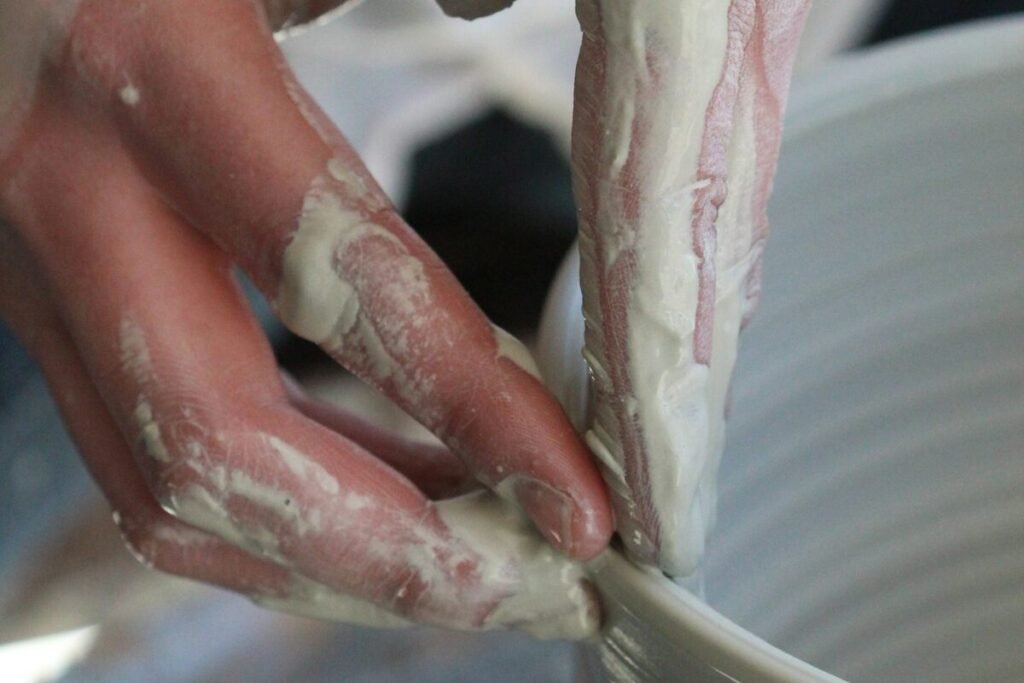 Hands shaping the rim of a ceramic bowl