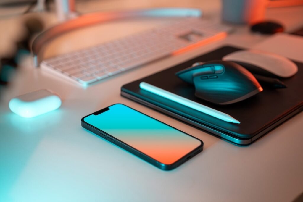 A laptop, mouse and phone laid out on a desk for comparison