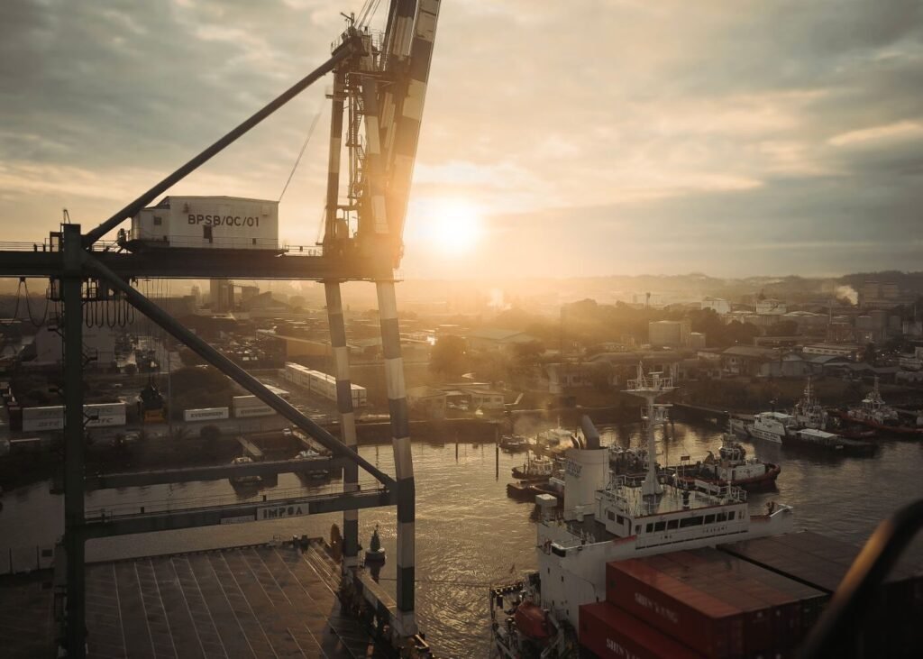 Sunset over a port with cranes and cargo ships