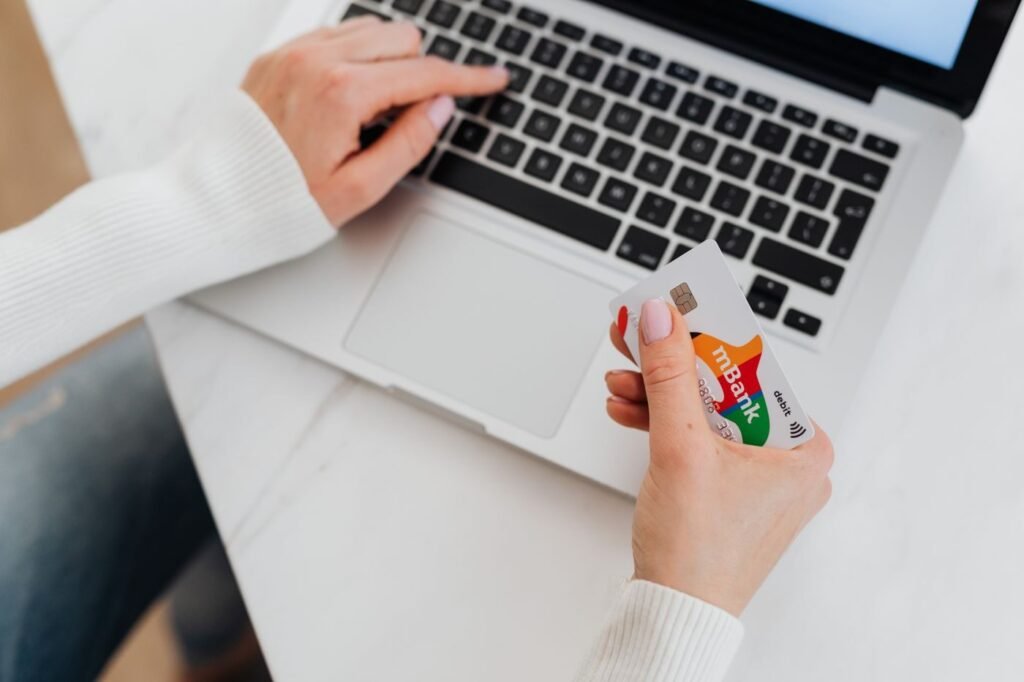 Shopper holding a bank card while buying on a laptop