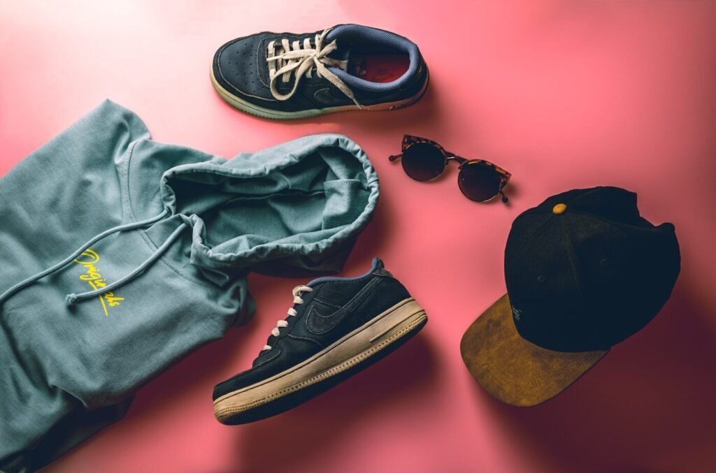 Sneakers beside a folded hoodie on a plain background