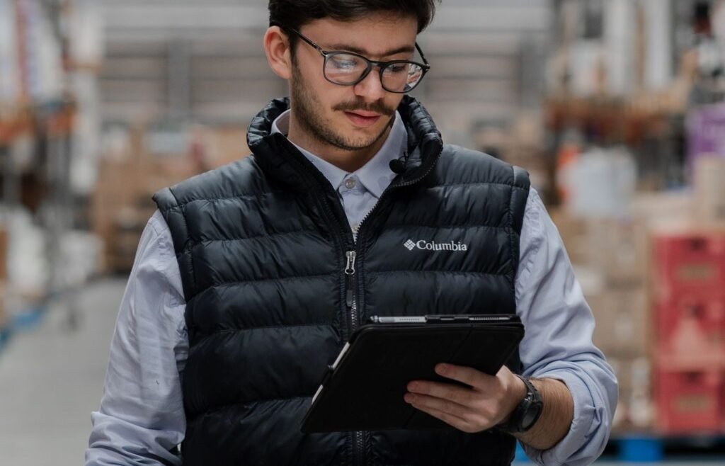 Warehouse worker checking stock levels on a tablet beside stacked inventory