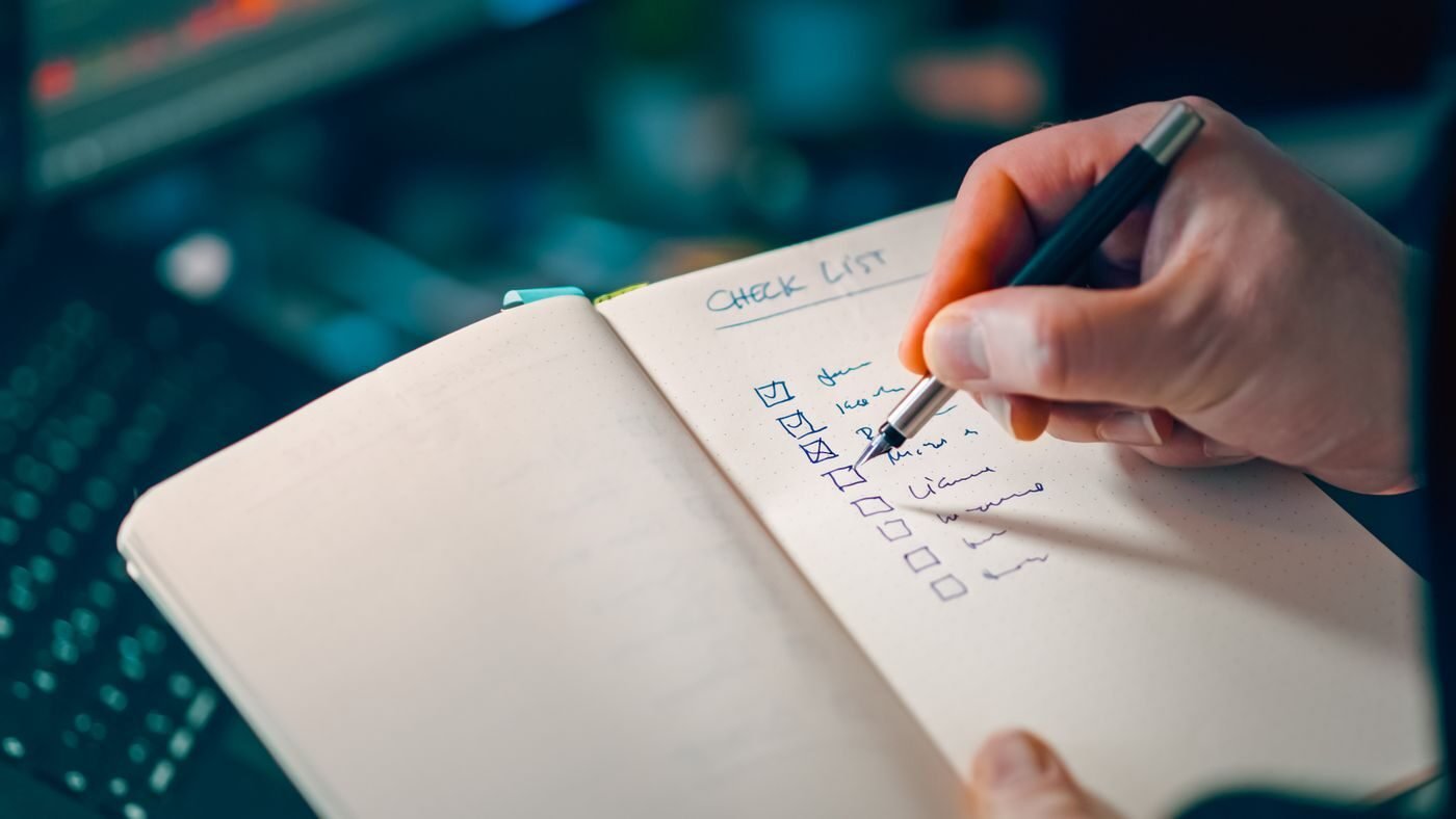Hand working through a written checklist in a notebook while planning eCommerce work