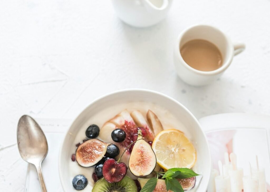 A fruit and yogurt bowl beside a cup of coffee