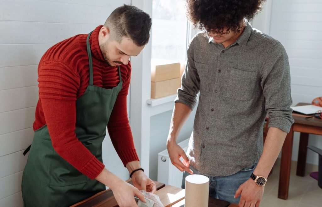 Two people packing and labelling parcels for marketplace fulfilment in a sunlit workspace