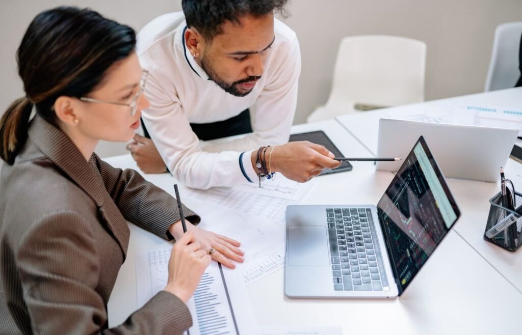 Two colleagues reviewing performance data on a laptop at a shared desk