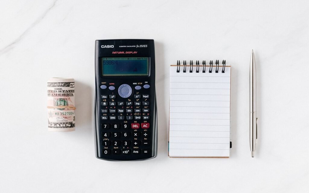 Calculator, banknotes and a notebook laid out for a paid media budget plan