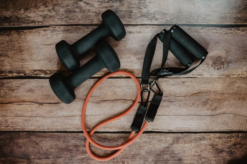 Dumbbells and a resistance band laid out on a wooden surface