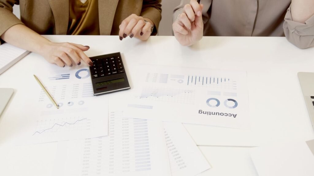 Two marketers checking campaign figures against the accounts with a calculator