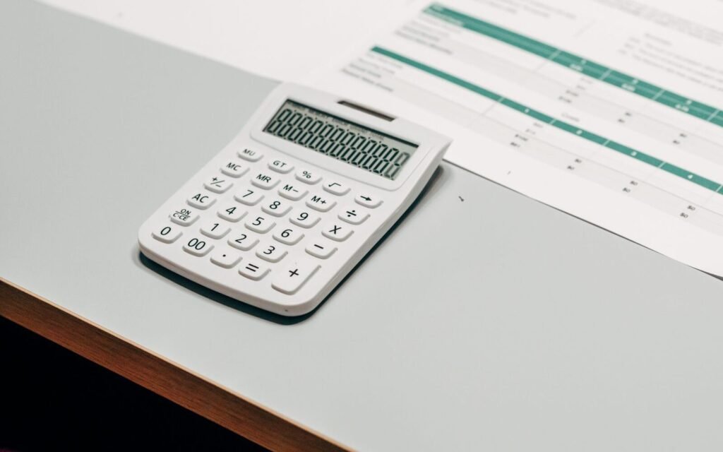 Calculator beside a margin spreadsheet on a desk, working out eCommerce profit per order