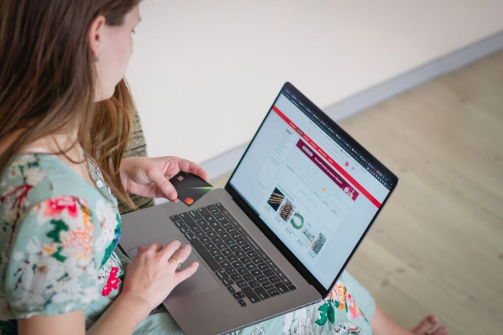 Shopper comparing products on a laptop with a payment card in hand
