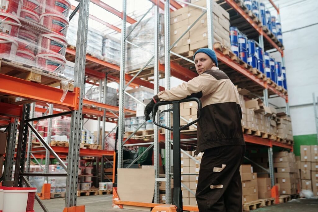 Warehouse worker moving pallets of marketplace orders with a pallet jack