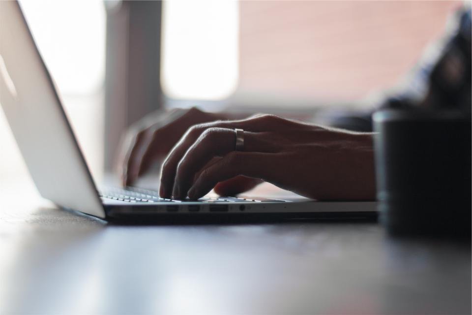 Hands typing on a laptop keyboard at a tidy desk